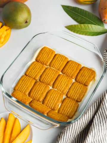 first layer of soaked cookies lined in a glass dish.