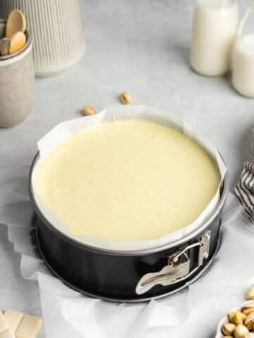 pistachio cheesecake filling in a lined cheesecake pan before going into the fridge to chill.