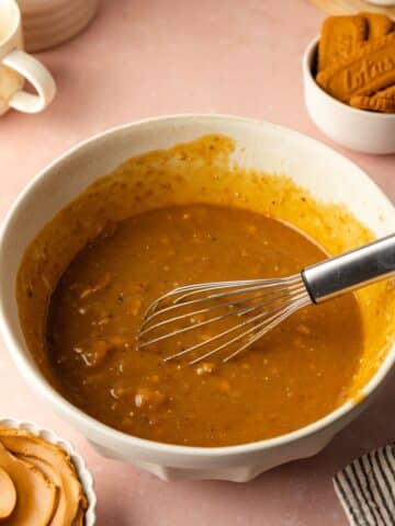 a large mixing bowl with biscoff spread, mashed banana, vanilla, soy milk and vinegar, and vegan yogurt whisked until smooth.