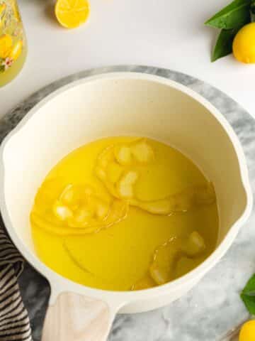 lemon syrup in a saucepan with whole lemon rind inside.