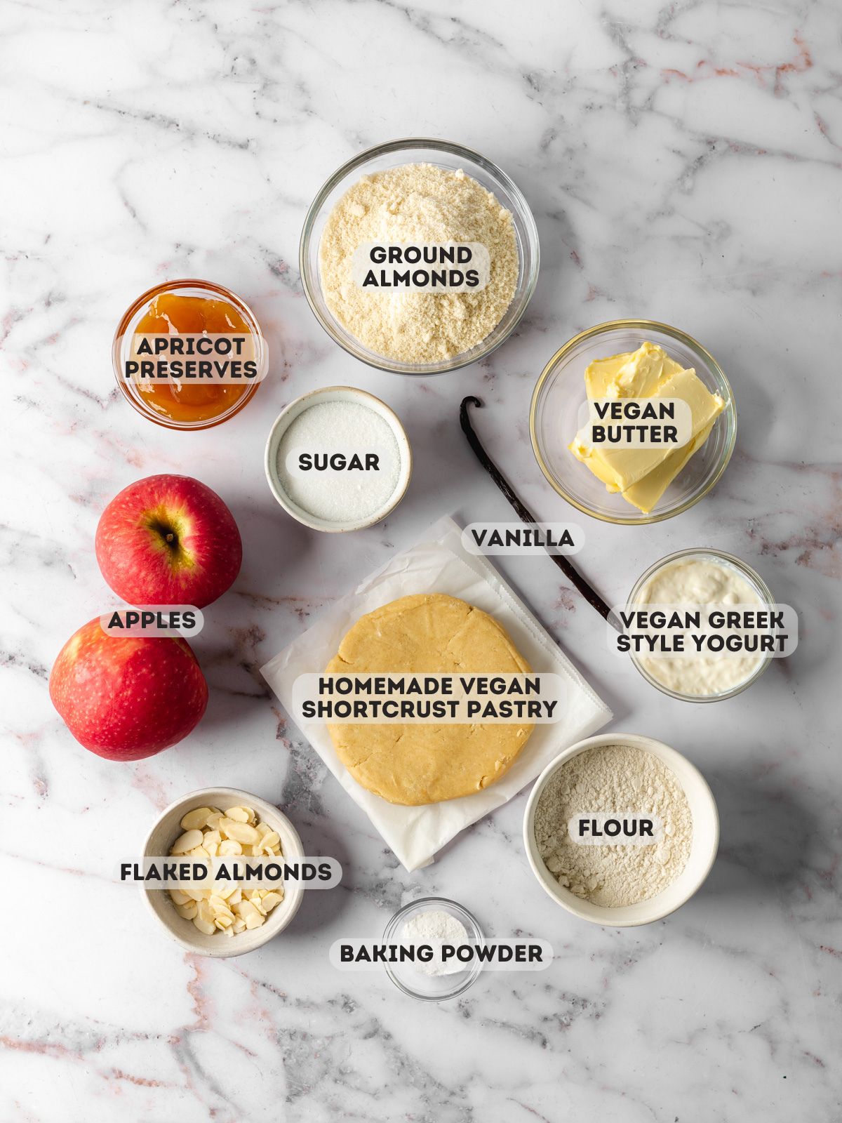 ingredients to make vegan apple tart measured out in bowls on a marble surface.