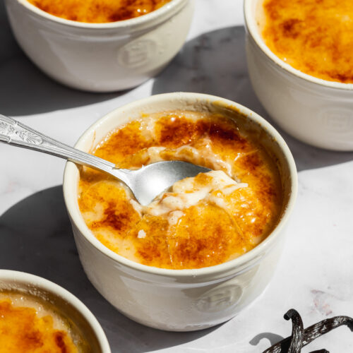 a creme brulee ice cream in a ceramic pot with a spoon inside showing the creamy consistency.