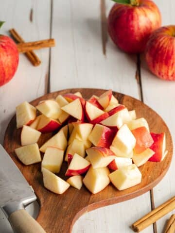 red apples chopped on a wooden cutting board.