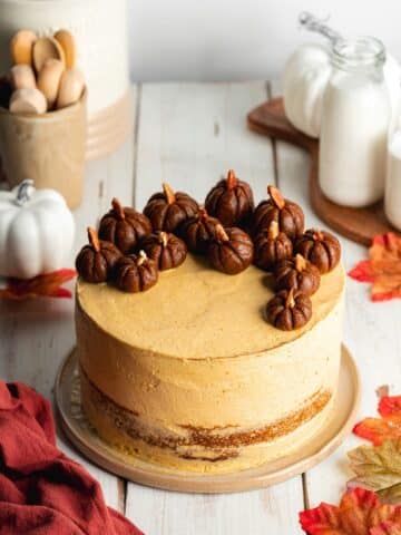 a pumpkin layer cake with pumpkin frosting and mini pumpkins on top.
