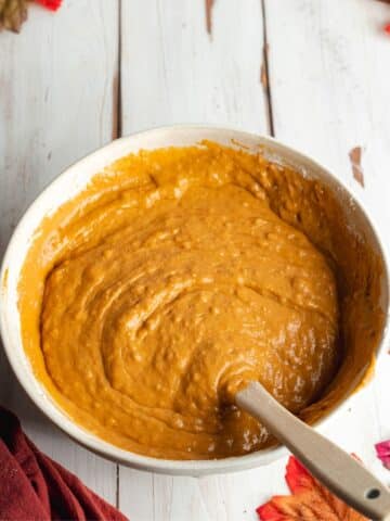 pumpkin cake batter in a ceramic bowl with a rubber spatula.