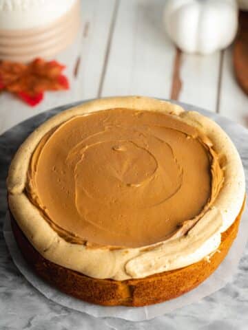 a pumpkin cake layer topped with biscoff spread filling and a dam of pumpkin frosting around the edges.
