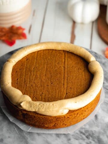a pumpkin cake layer with a dam of pumpkin frosting around the edge.