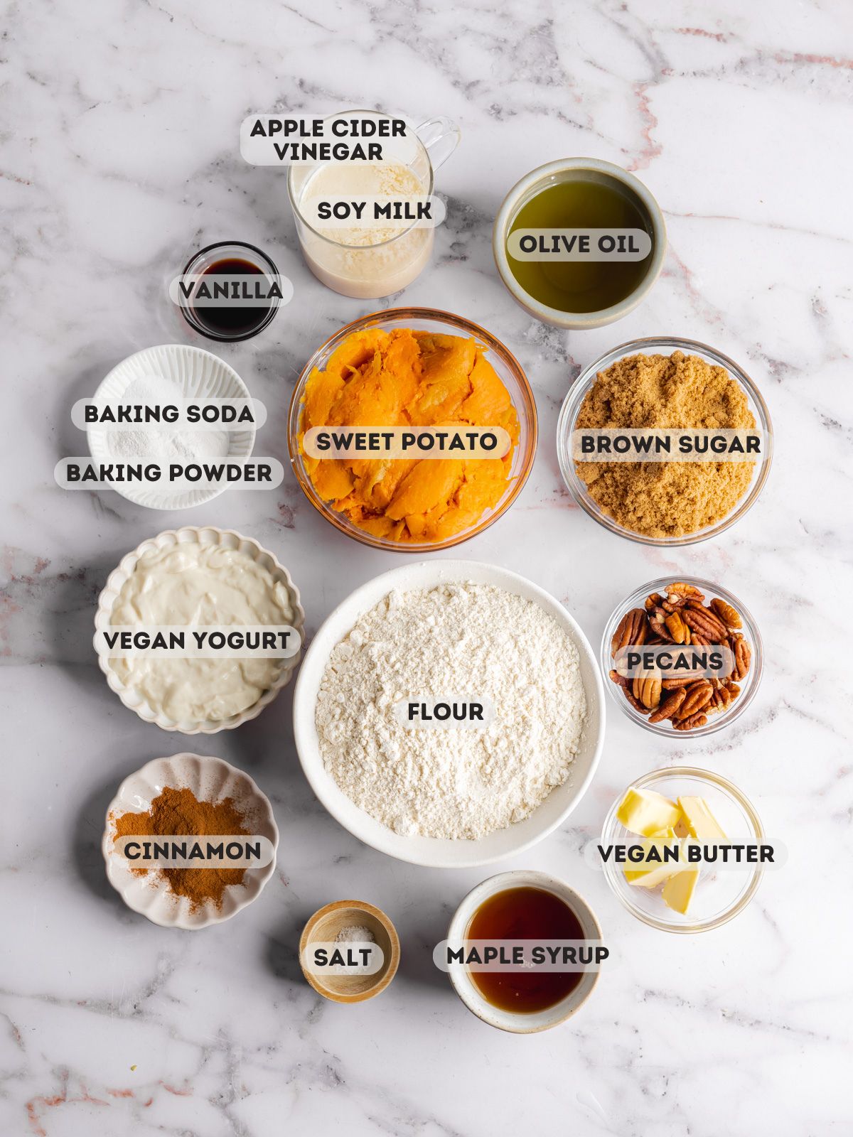 ingredients to make sweet potato muffins measured out in bowls on a marble surface.
