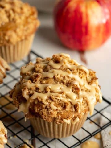 apple muffin on a wire rack with maple glaze drizzled on top.