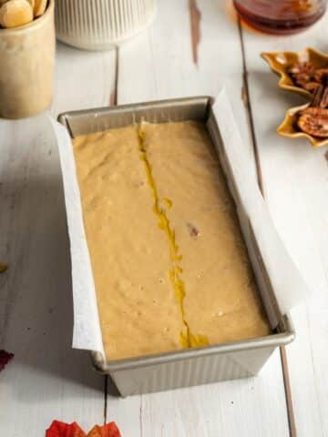pecan bread batter in a parchment paper lined loaf pan before baking.
