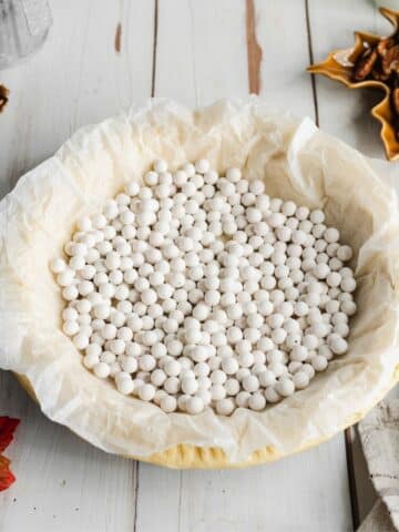 pie crust filled with parchment paper and baking beads before blind baking.