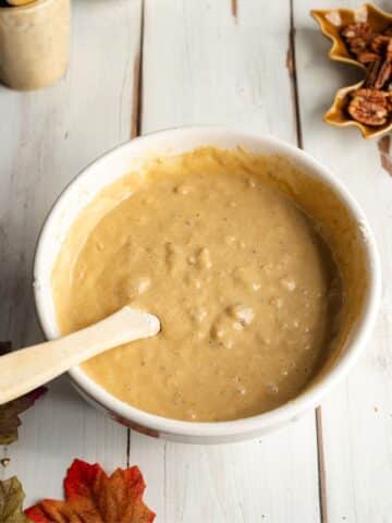 pecan bread batter in a white mixing bowl with a rubber spatula.