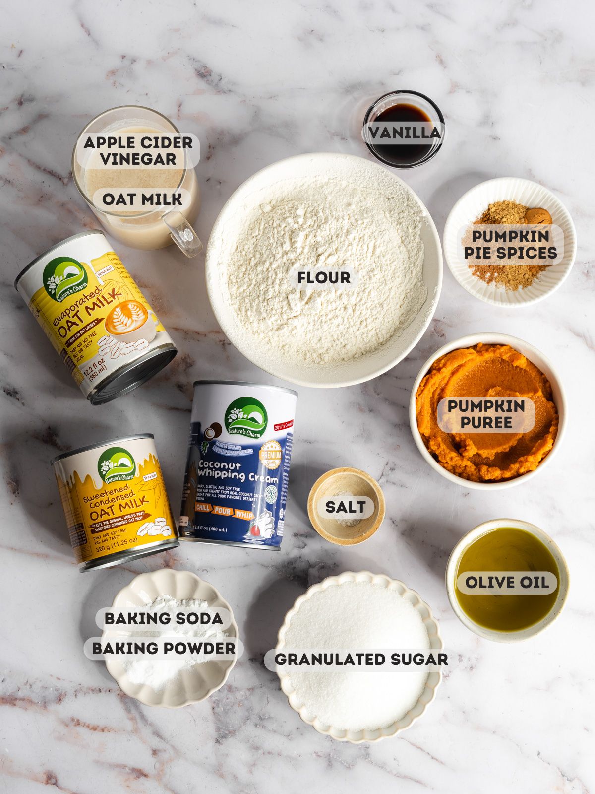 ingredients for pumpkin tres leches measured out in bowls on a marble surface.