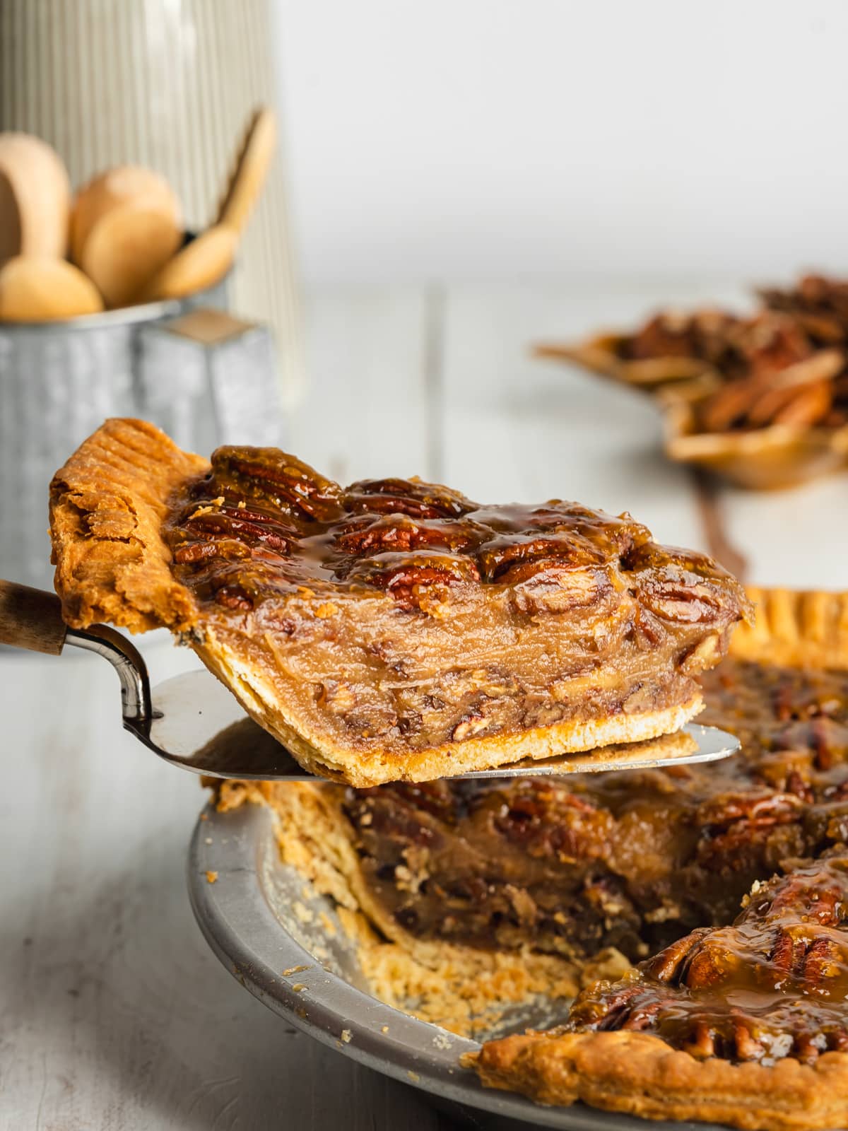 a slice of deep-dish pecan pie begin lifted away from the pan with a cake slice.