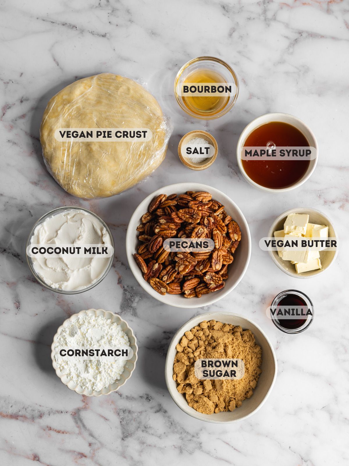 ingredients to make vegan pecan pie measured out in bowls on a marble surface.