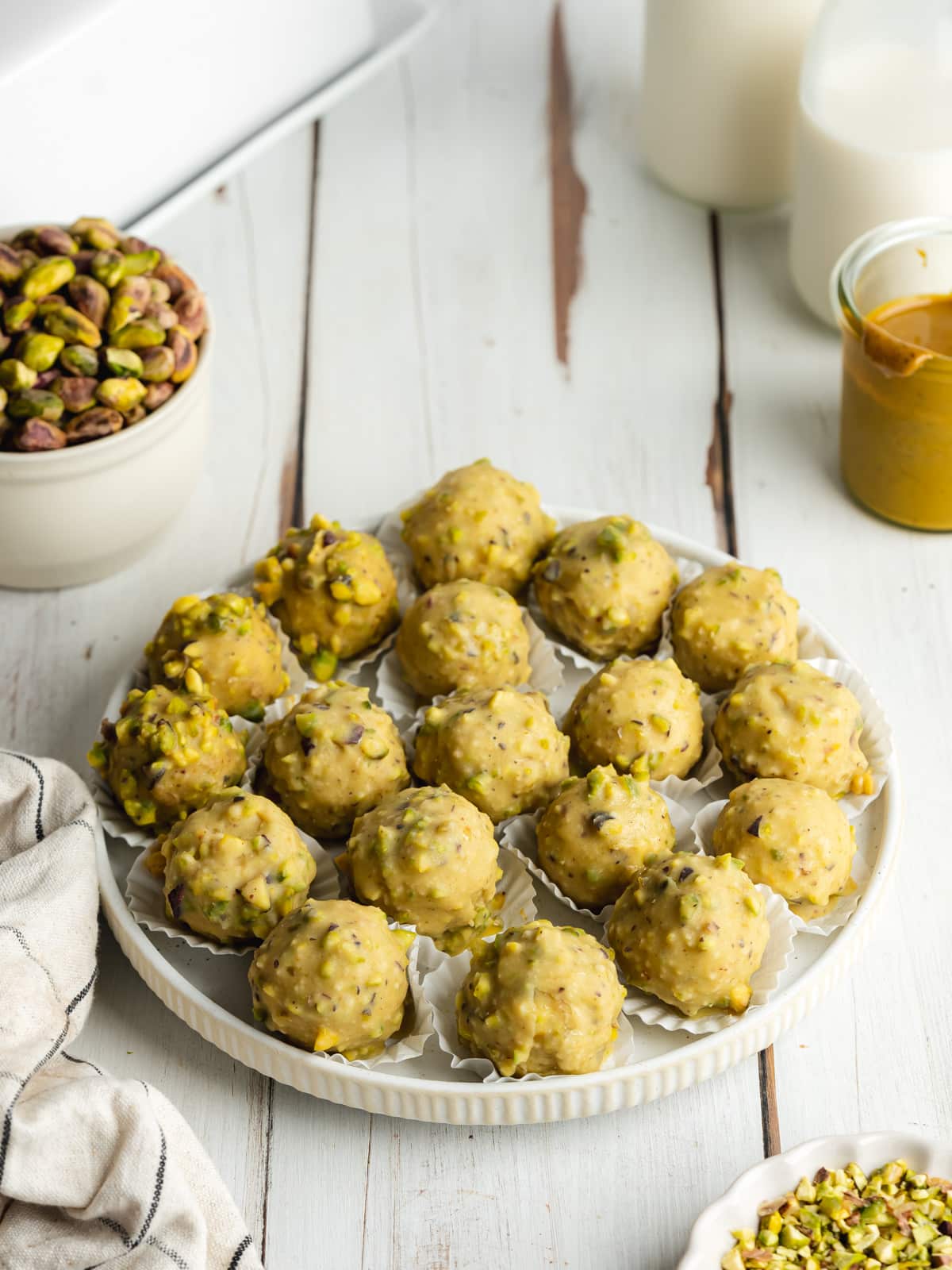 homemade pistachio white chocolate truffles on a ceramic plate on a wooden table.
