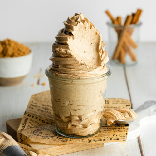 a weck jar filled with piped brown sugar frosting and cinnamon sticks and brown sugar scattered around the scene.