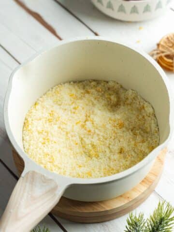 sugar with orange and lemon zest rubbed into it in a white saucepan.