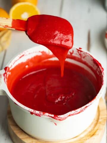 cranberry curd in a saucepan coating the back of a spatula.