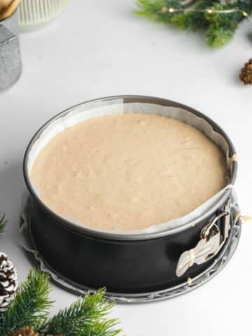 a cheesecake pan lined with parchment paper and filled with gingerbread cream cheese batter.