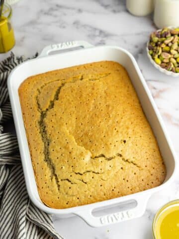 pistachio sheet cake with holes poked into it before adding milk soak.