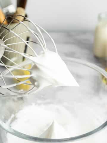 aquafaba whipped to stiff peaks in a stand mixer bowl.