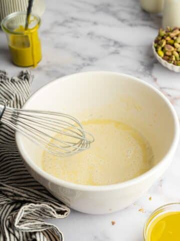wet ingredients for pistachio milk cake whisked in a bowl.