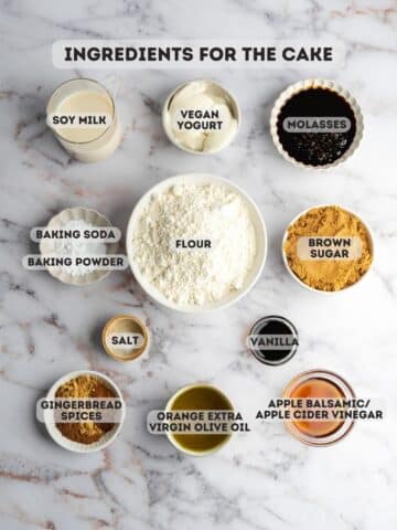 ingredients for gingerbread olive oil cake measured out in bowls on a marble table.