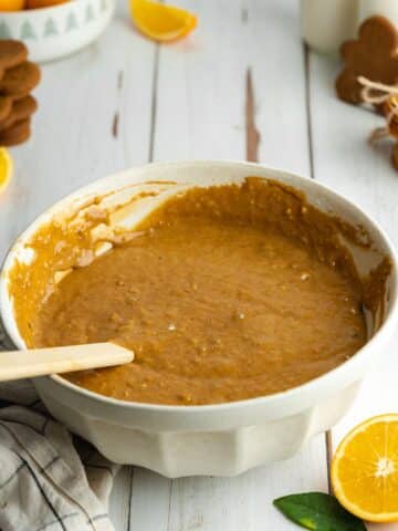 gingerbread cake batter in a large ceramic bowl with a spatula.