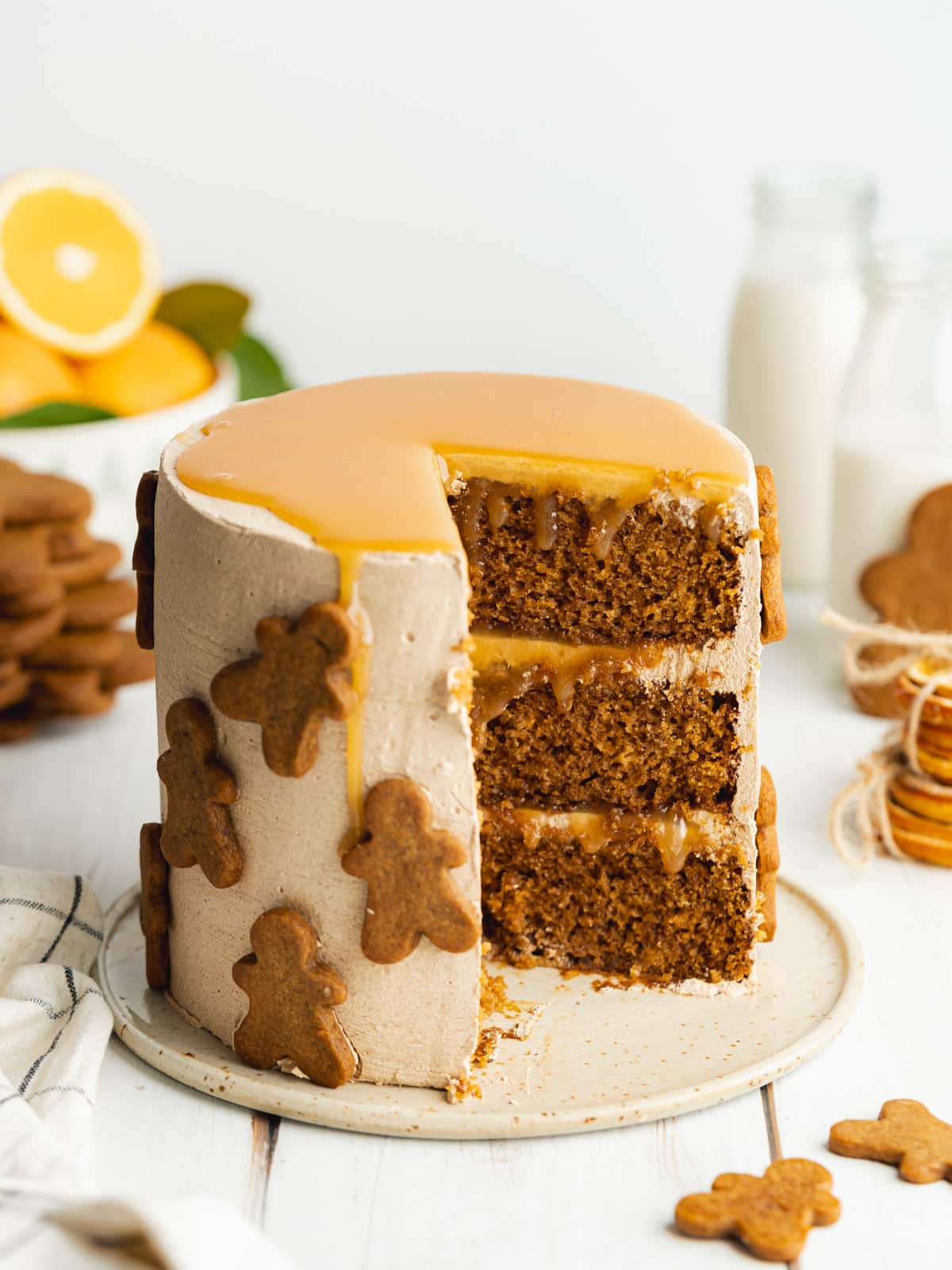 orange caramel gingerbread caramel cake on a ceramic plate with a few slices missing, exposing all the layers inside the cake.