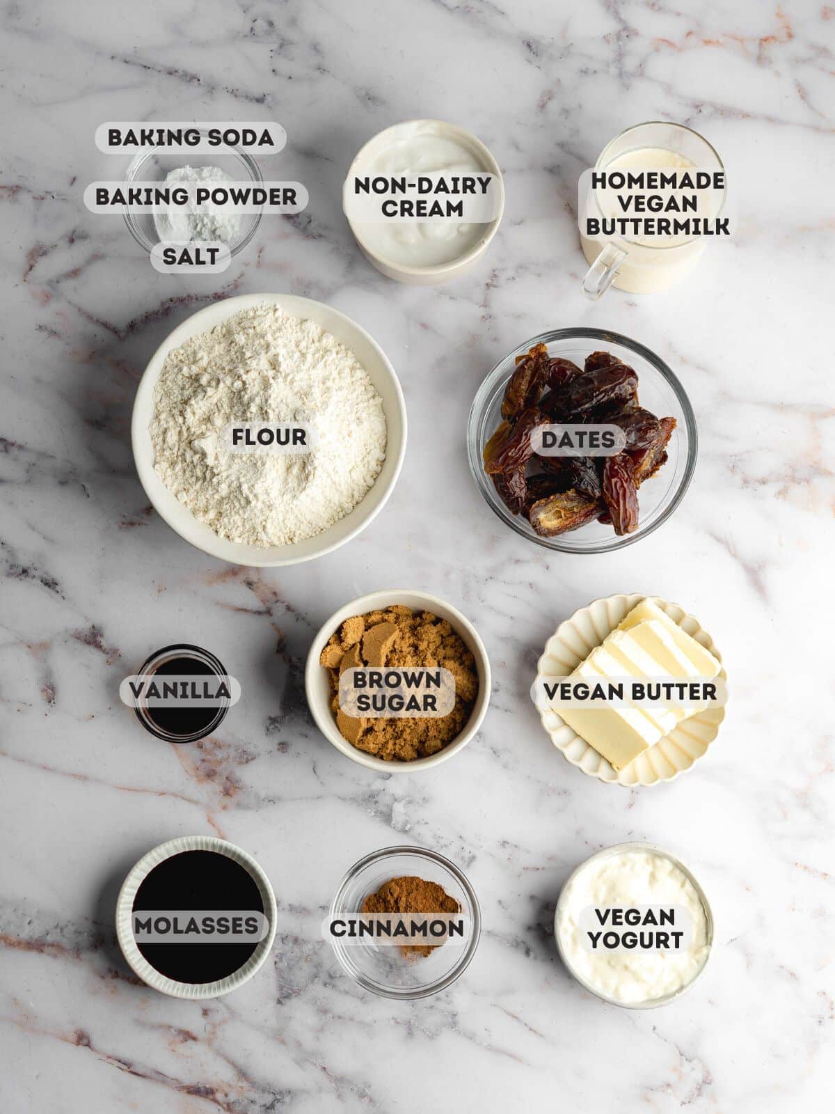 ingredients to make sticky date pudding measured out in bowls on a marble surface.