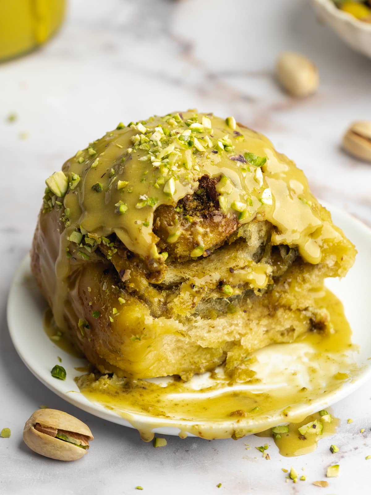 pistachio cinnamon roll with a bite taken from it showing the gooey center.