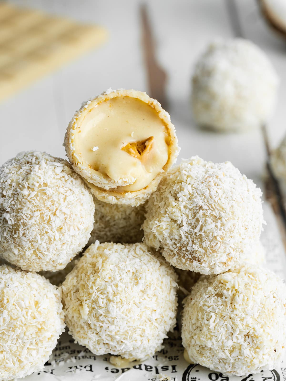 vegan coconut balls in a stack with one cut in half to show the creamy filling.