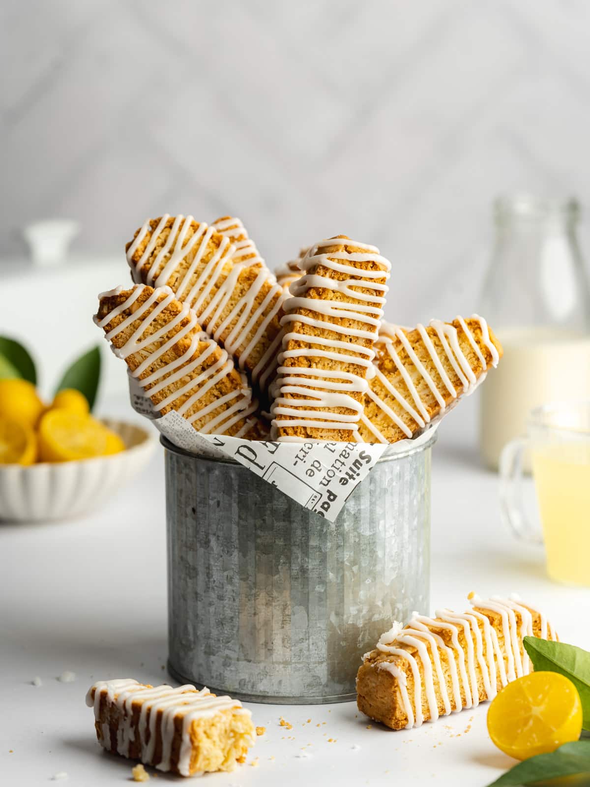 lemon biscotti drizzled with limoncello icing in a metal jug.