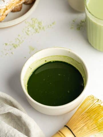 matcha powder, vanilla, and hot water mixed in a small bowl.