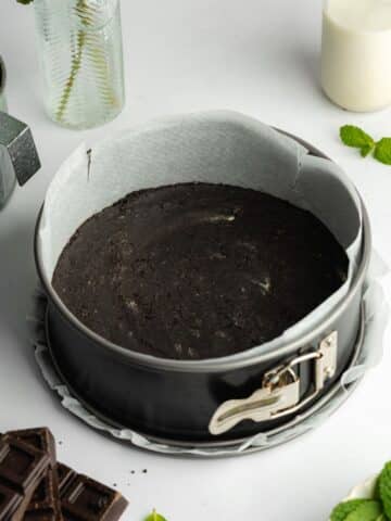 oreo cookie crust pressed into the base of a parchment-lined springform pan.