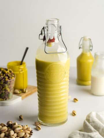 a large glass bottle of homemade pistachio liqueur.