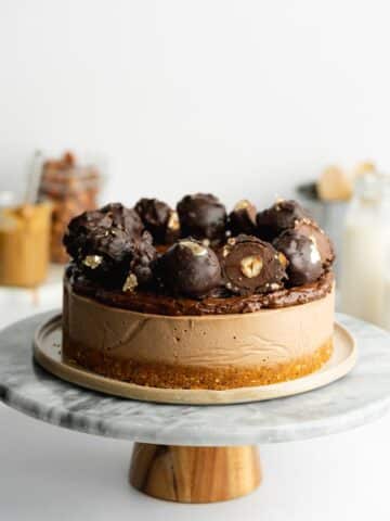 hazelnut no-bake cheesecake topped with chocolate ganache and homemade vegan ferrero rocher.