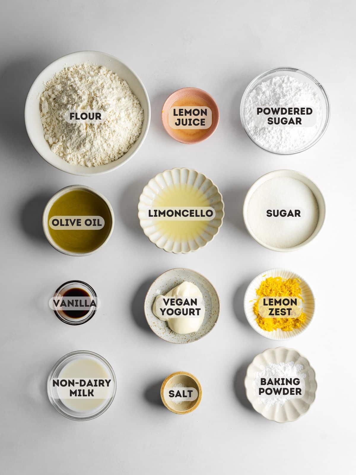 ingredients to make lemon biscotti measured out in bowls on a gray table.