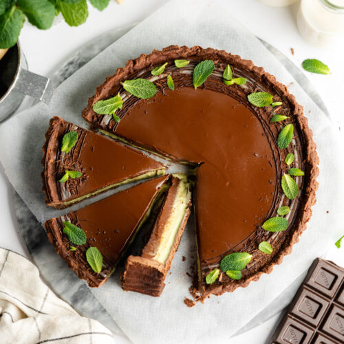 flatlay of sliced mint chocolate tart with fresh mint leaves.