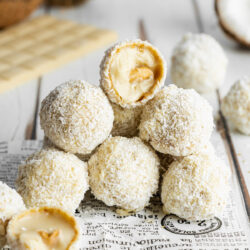 a stack of homemade raffaello with a bite taken from the one on top showing the creamy center.