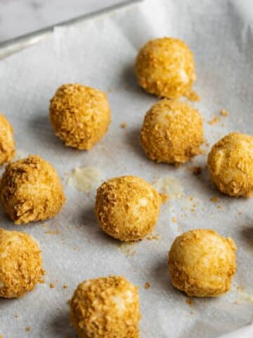 coconut balls coated with finely chopped wafers on a tray lined with parchment.
