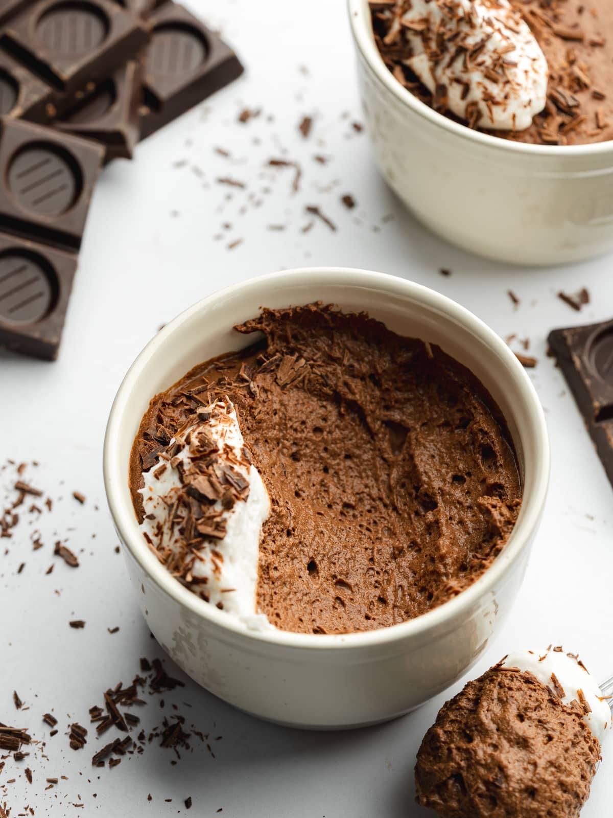 a small cream ramekin with chocolate mousse and dark chocolate bars scattered around it.