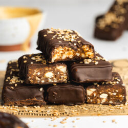 a stack of chocolate-covered date bars on some brown newspaper.