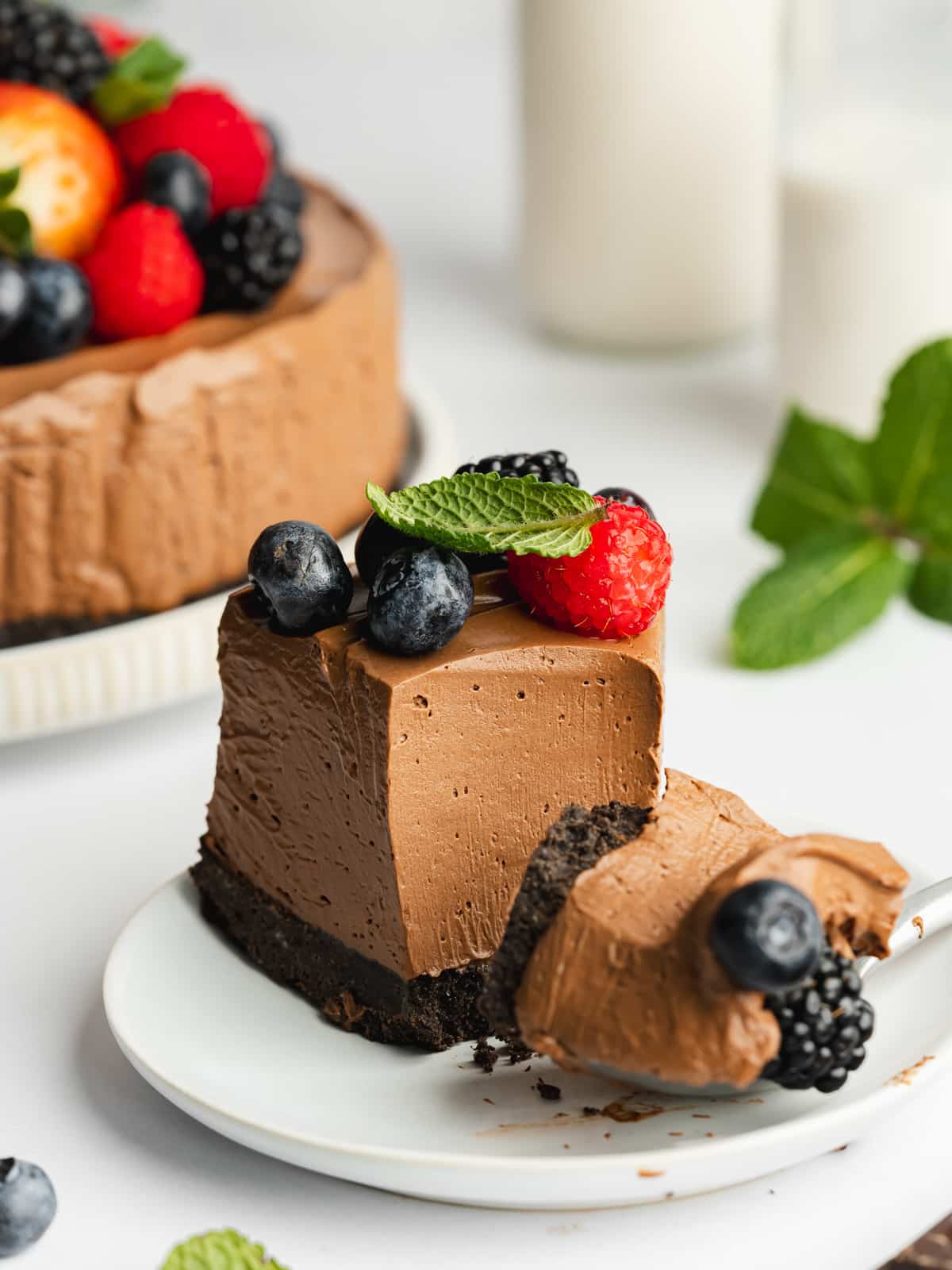 a slice of no-bake chocolate mousse cake topped with berries with a spoonful taken showing the creamy consistency.