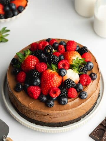 chocolate mousse cake topped with fresh berries on a white plate.