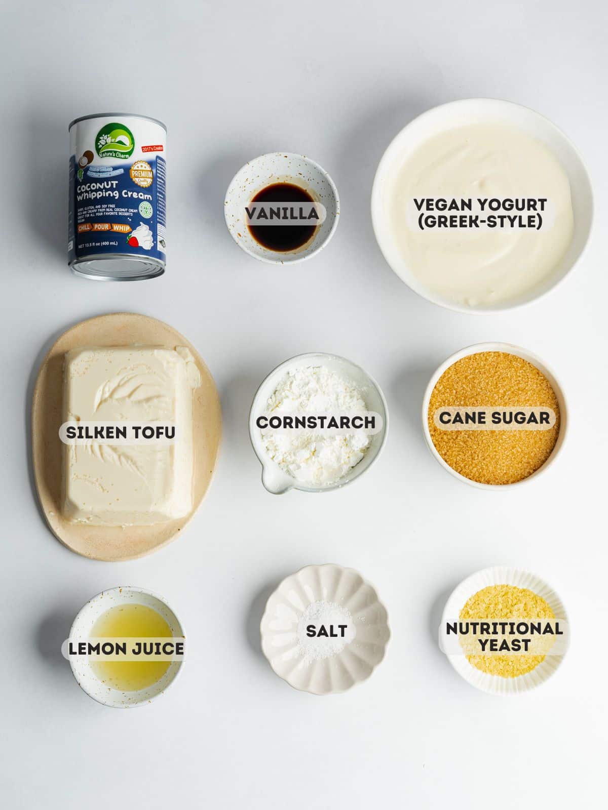 ingredients for vegan basque cheesecake measured out in bowls on a gray surface.