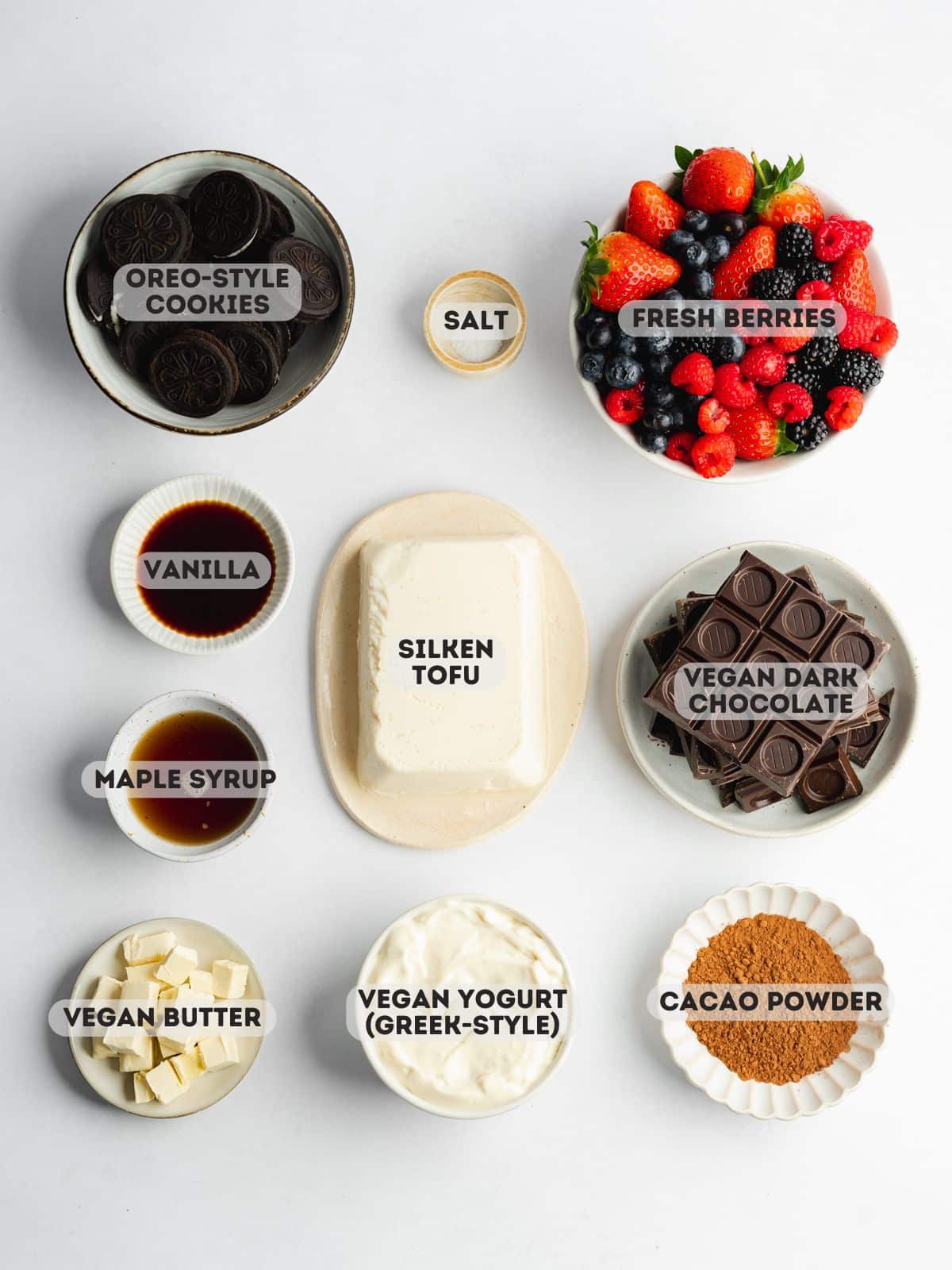 ingredients to make chocolate mousse cake measured out and labeled in bowls on a white surface.