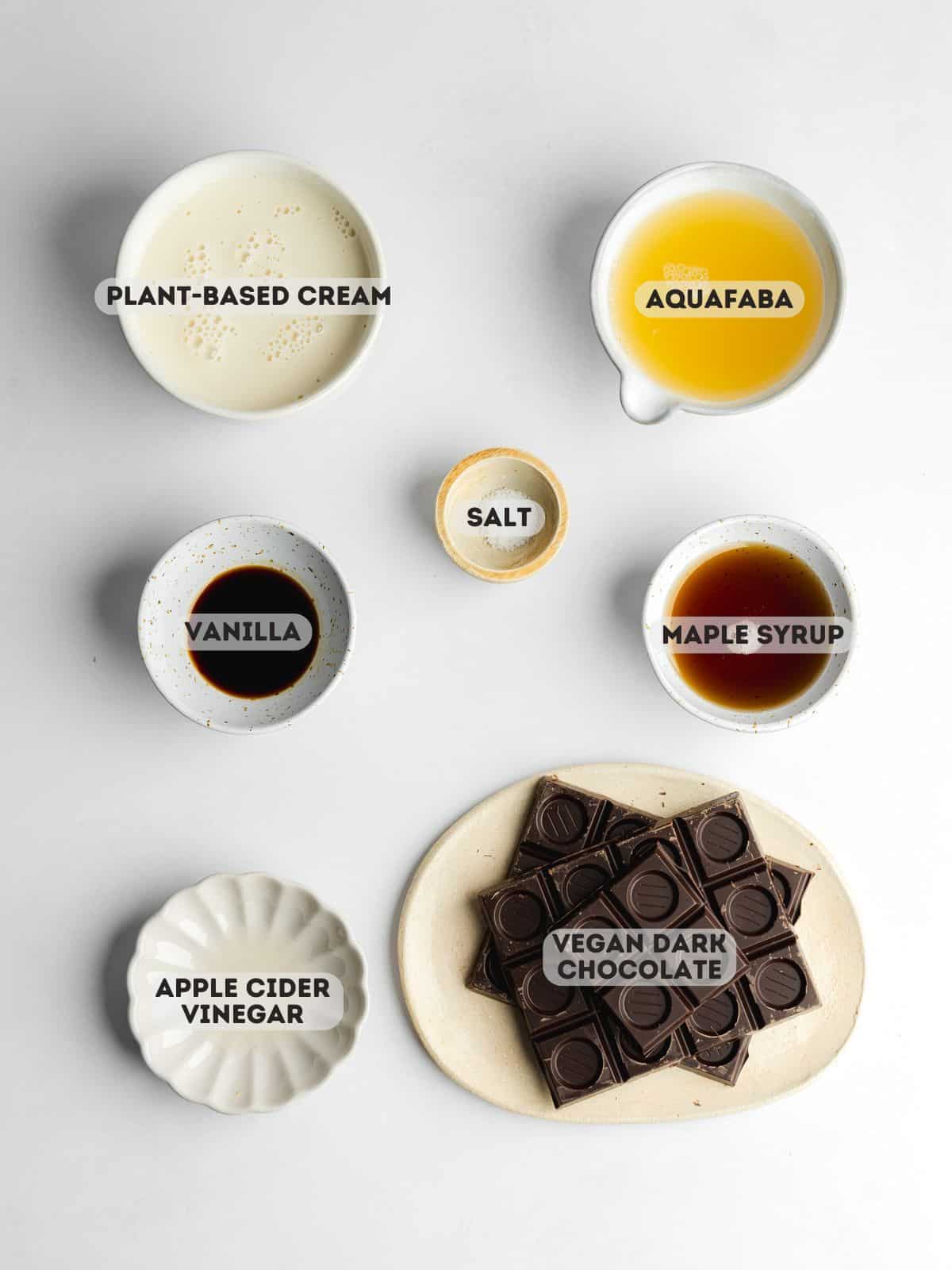 ingredients for vegan chocolate mousse measured in bowls on a white surface.
