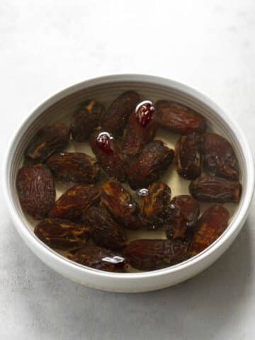 whole medjool dates in a bowl soaking in warm water.